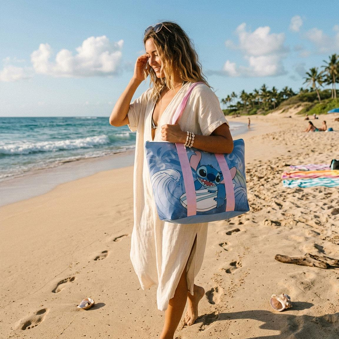 Borsa mare a tema Stitch celeste con la scritta "Stitch's Surf", Stitch su una tavola da surf e i manici rosa. Foto della borsa indossata al mare da una donna 